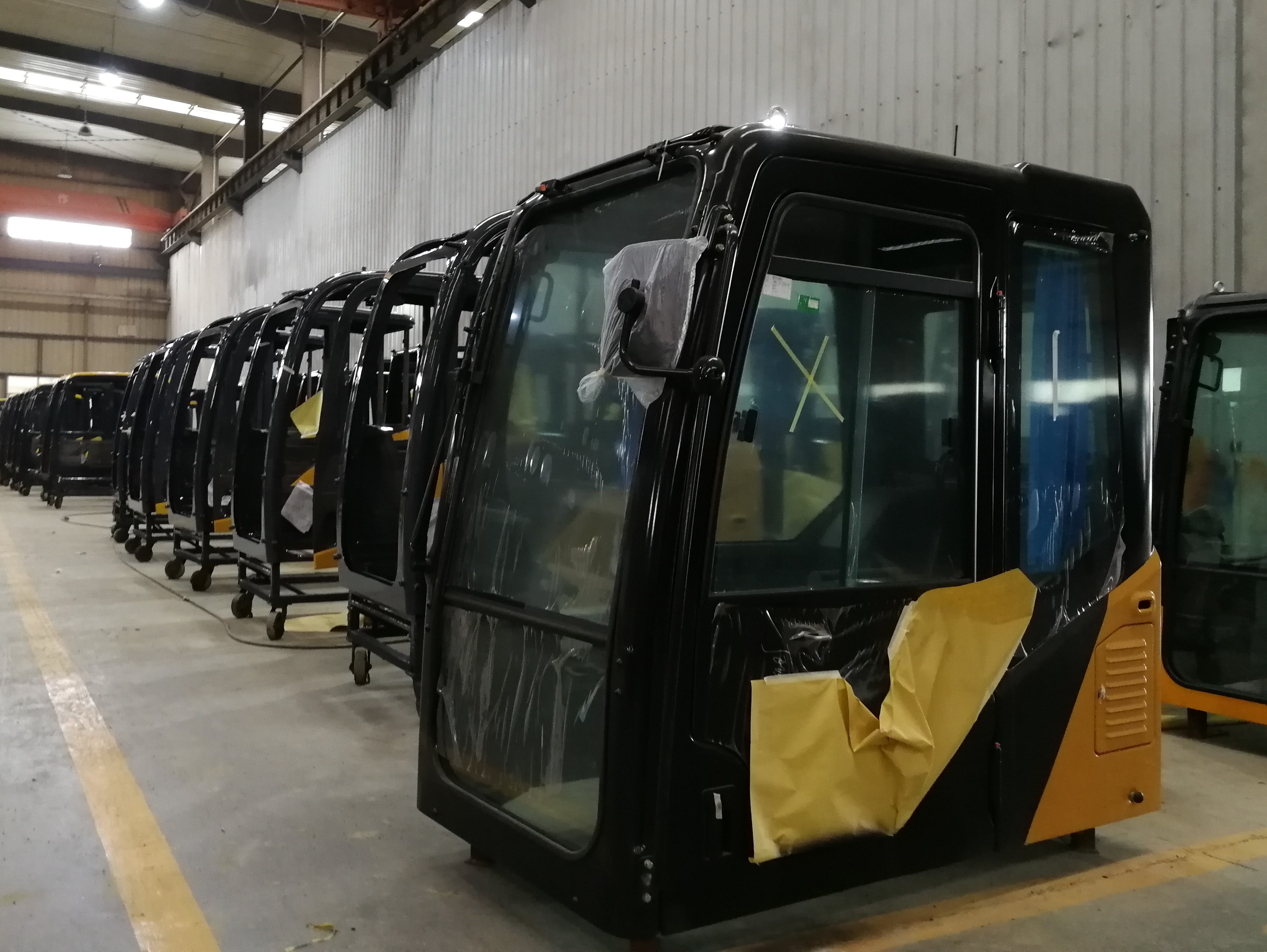 Heavy machinery operator cabins staged in a manufacturing facility