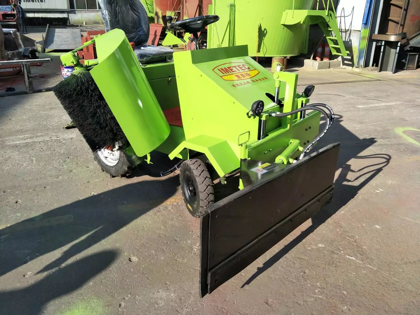 Electric feed pusher with front-mounted blade and side brush