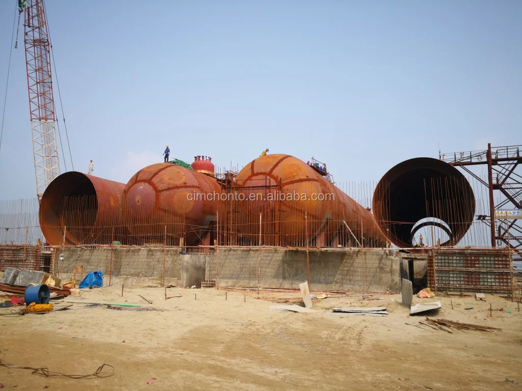 Workers and heavy machinery on a mounded tank construction site
