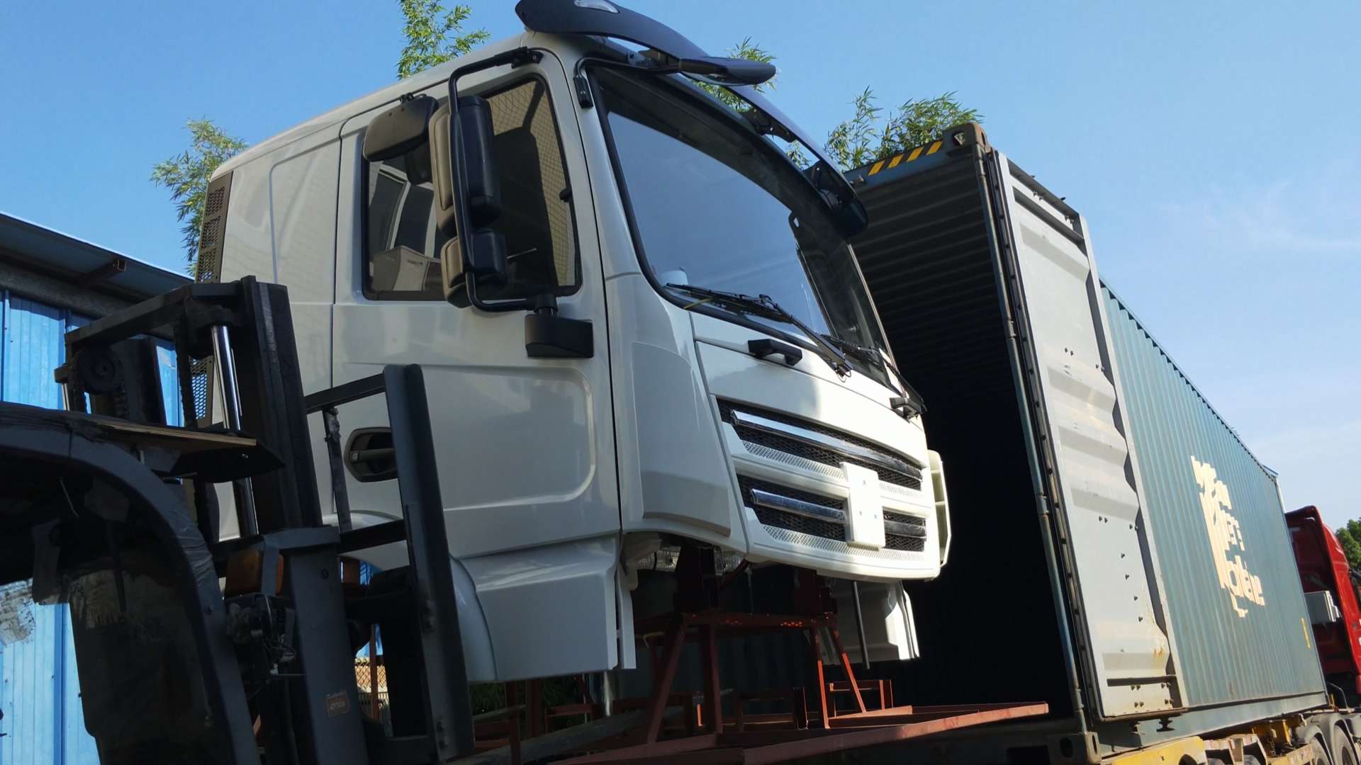 White truck cab being loaded onto a shipping container